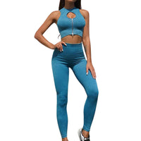 Frau in blauem Sport-Set mit Reißverschluss, ärmelloses Top, Leggings, Fitnessmode.