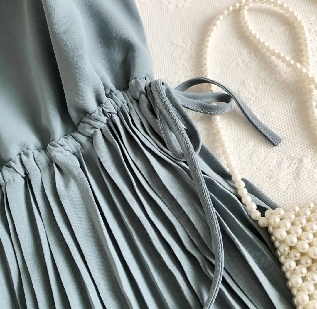 Graues plissiertes Kleid aus Chiffon mit Perlenkette auf Spitze, elegantes Damenoutfit.