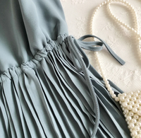 Graues plissiertes Kleid aus Chiffon mit Perlenkette auf Spitze, elegantes Damenoutfit.