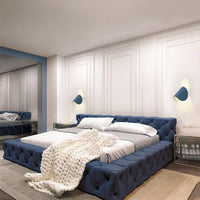 Luxus Schlafzimmer mit blauem Polsterbett, weißer Bettwäsche und gestrickter Decke.