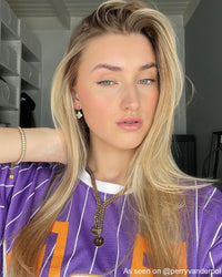 Frau mit goldenen Ohrringen und Ketten, lila gestreiftes Shirt, modisches Accessoire.