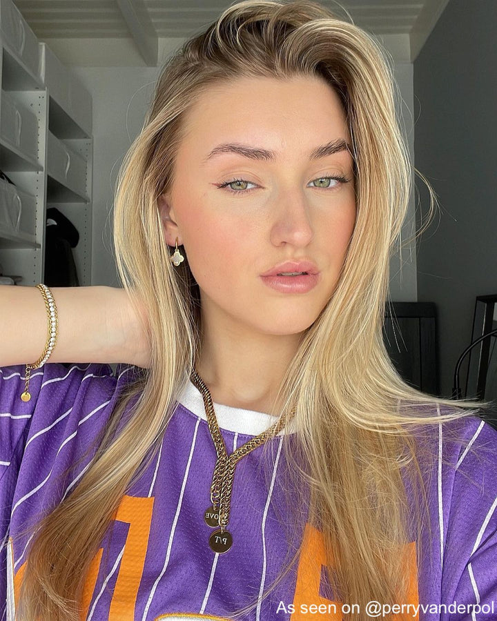 Frau mit goldenen Ohrringen und Ketten, lila gestreiftes Shirt, modisches Accessoire.