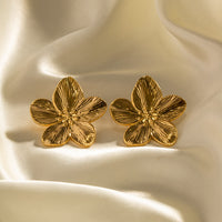 Goldene Blumen-Ohrringe auf Seide, eleganter Schmuck, luxuriöses Design, Damenaccessoire.