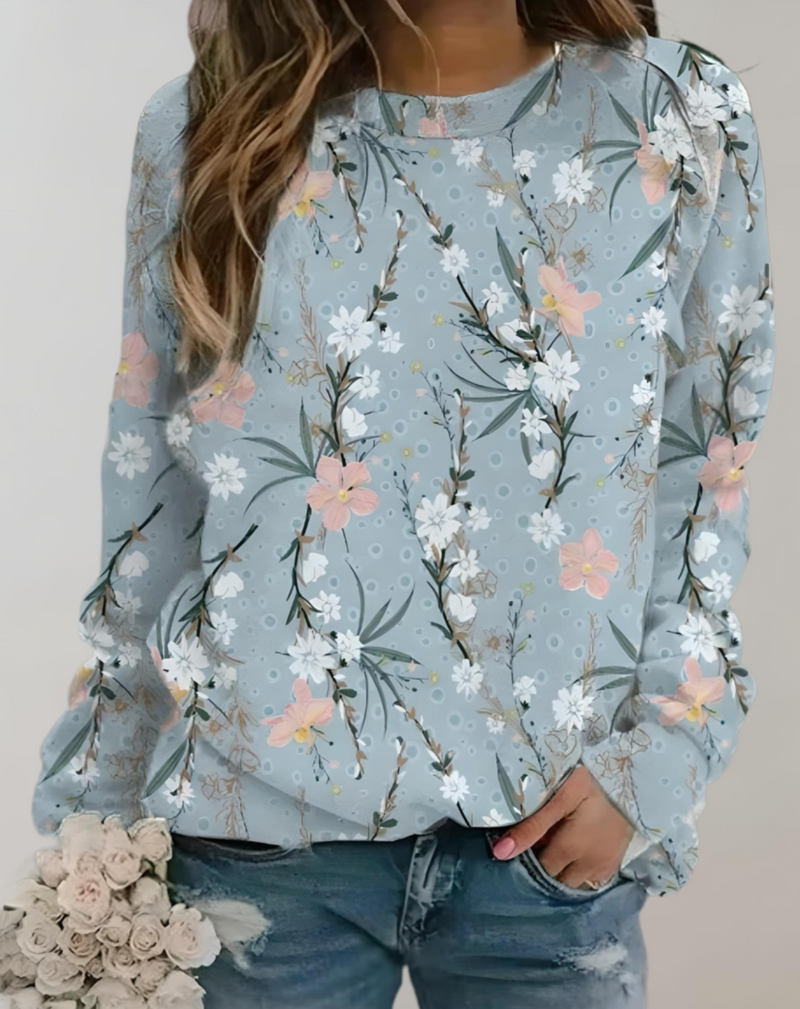 Frau in blauer Blumenbluse mit rosa und weißen Blüten, lässig, modisch, Jeans, Blumenstrauß.