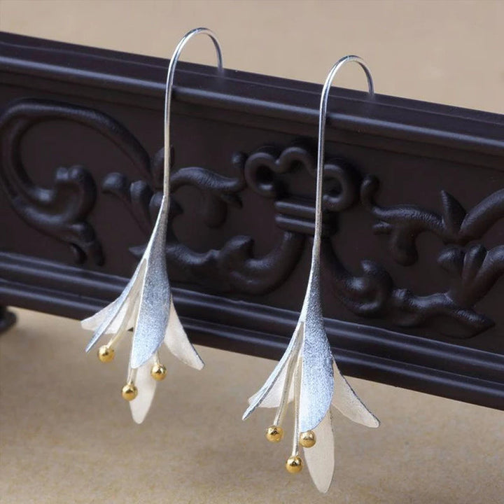 Lange silberne Blumenohrringe mit goldenen Akzenten, eleganter Schmuck für Frauen.