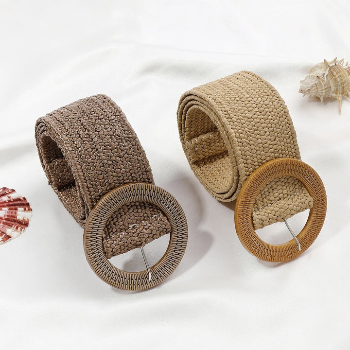 Zwei Boho-Stil Strohgürtel, beige und braun, mit runden Schnallen auf weißem Hintergrund.