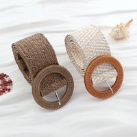 Zwei geflochtene Boho-Gürtel aus Stroh mit runden Schnallen auf weißem Hintergrund.