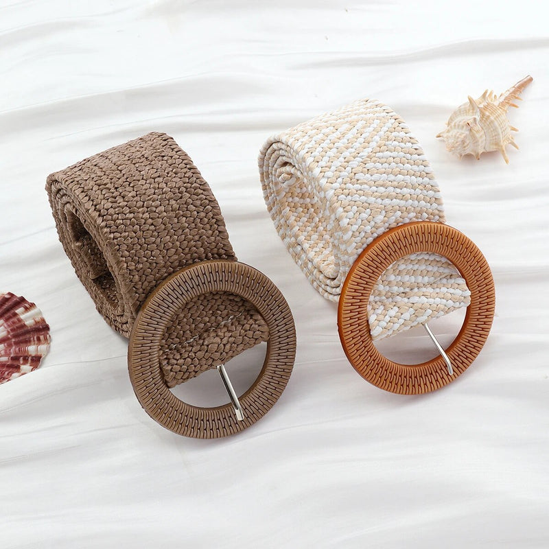 Zwei geflochtene Boho-Gürtel aus Stroh mit runden Schnallen auf weißem Hintergrund.