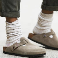 Beige Wildleder-Schlupfclogs mit verstellbarer Schnalle, getragen mit weißen Socken.