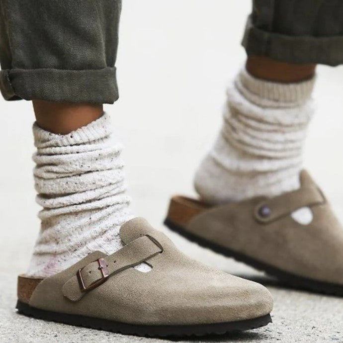Beige Wildleder-Schlupfclogs mit verstellbarer Schnalle, getragen mit weißen Socken.
