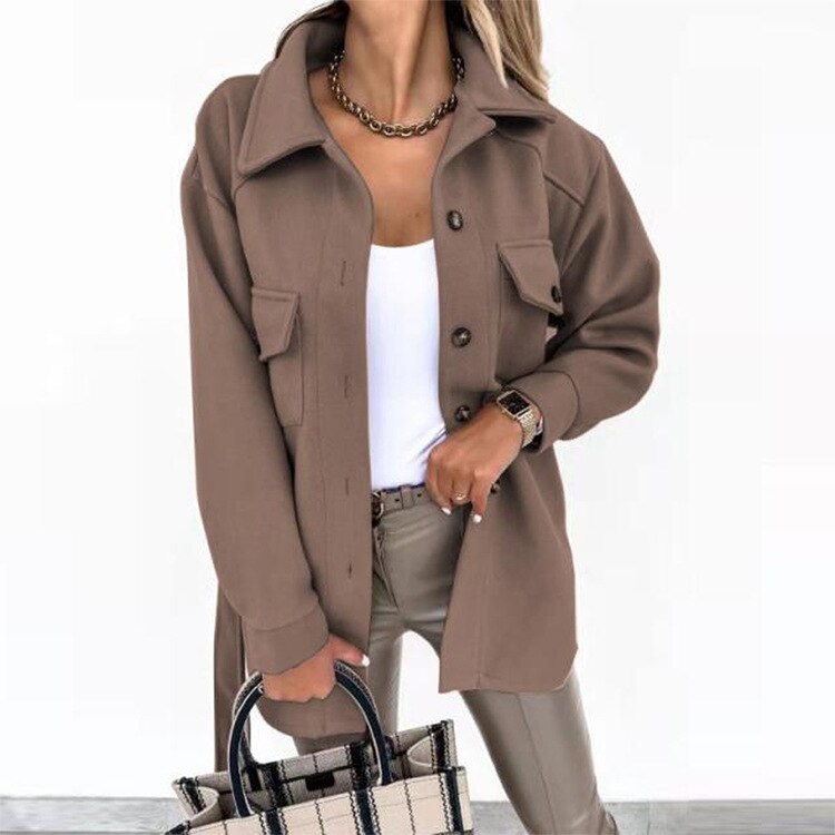 Frau in brauner Jacke, weiße Bluse, Lederhose, hält karierte Tasche, modisch, elegant.