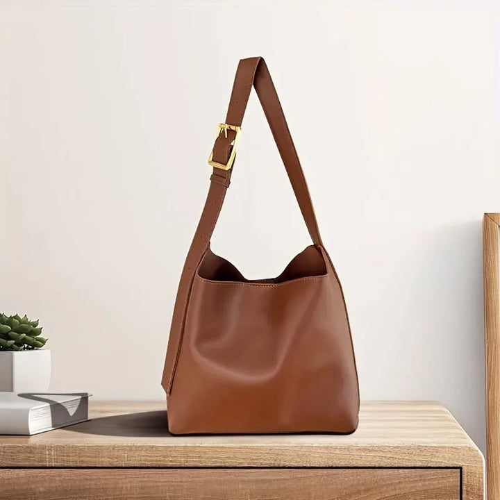 Braune Ledertasche mit verstellbarem Riemen auf Holztisch, elegantes Design, Damenmode.