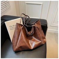 Braune Ledertasche auf schwarzem Sofa, stilvoll, geräumig, modisches Accessoire, Damenhandtasche.