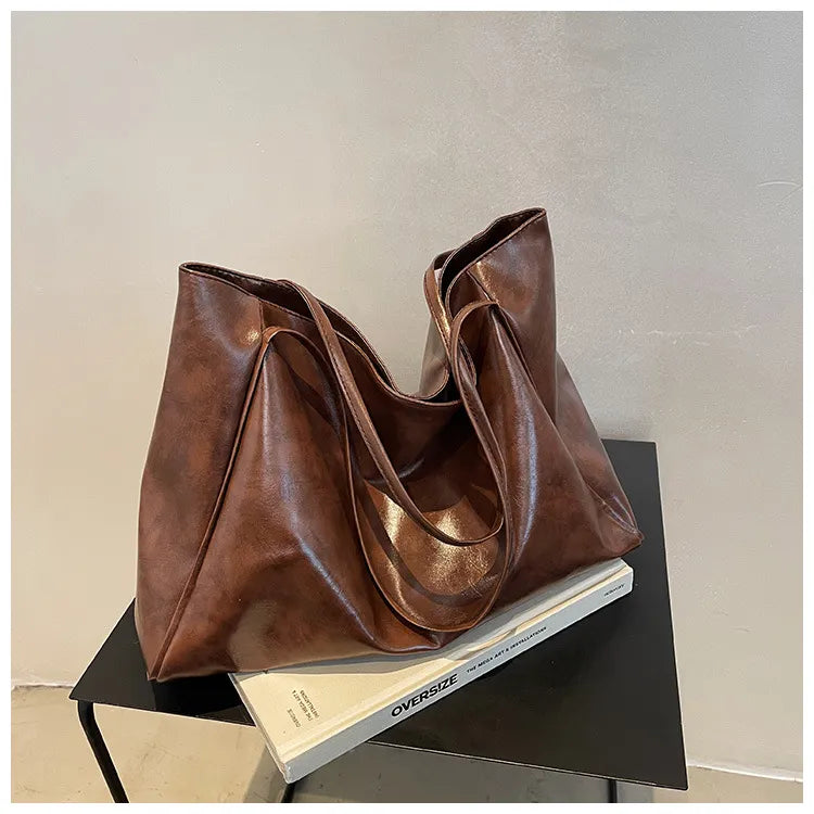 Braune Ledertasche auf Tisch, modisch, geräumig, Damenhandtasche, elegantes Design, Alltagsgebrauch.
