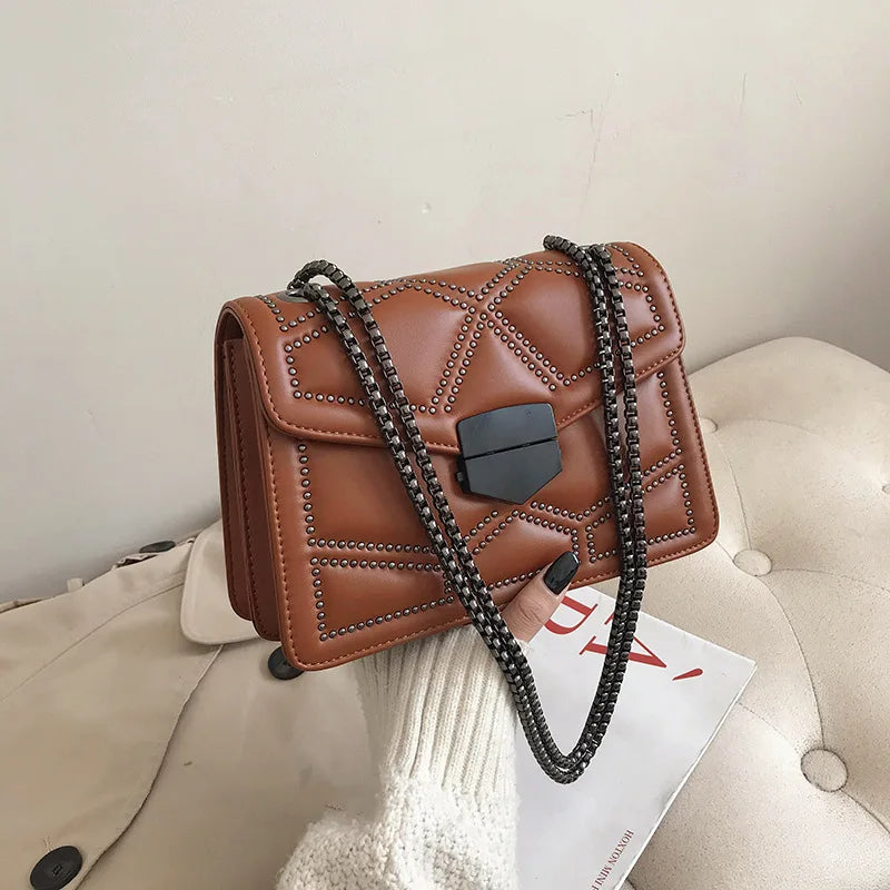 Braune Lederhandtasche mit Kettenriemen auf beigem Sofa, stilvoll und elegant.