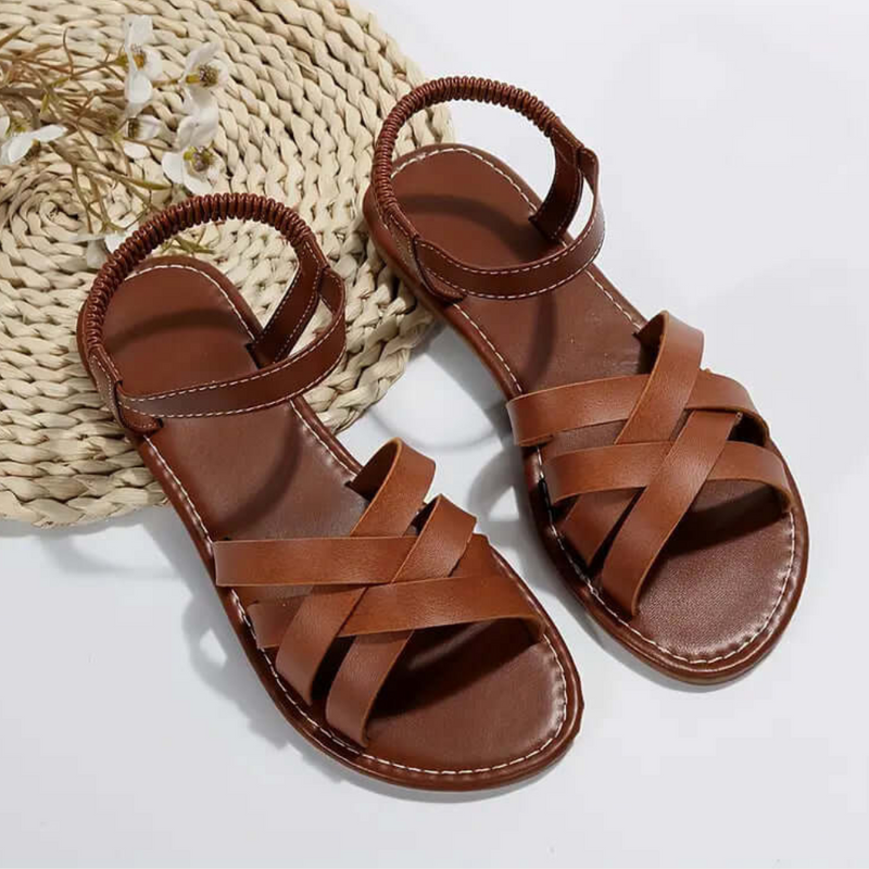 Braune Ledersandalen mit geflochtenem Riemen auf geflochtenem Untergrund, Damenmode, Sommer.