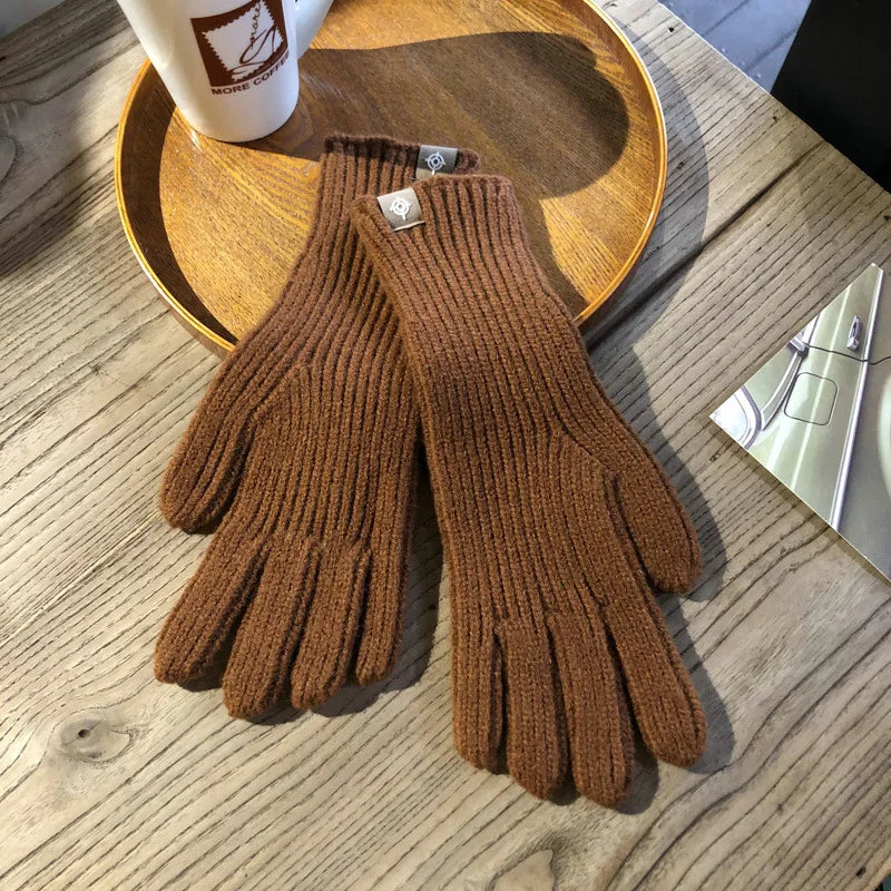 Braune Strickhandschuhe aus Wolle auf Holztisch, ideal für Wintermode und kaltes Wetter.