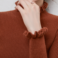 Frau in braunem Strickpullover mit Rüschenkragen, trägt eleganten Ring, Herbstmode.