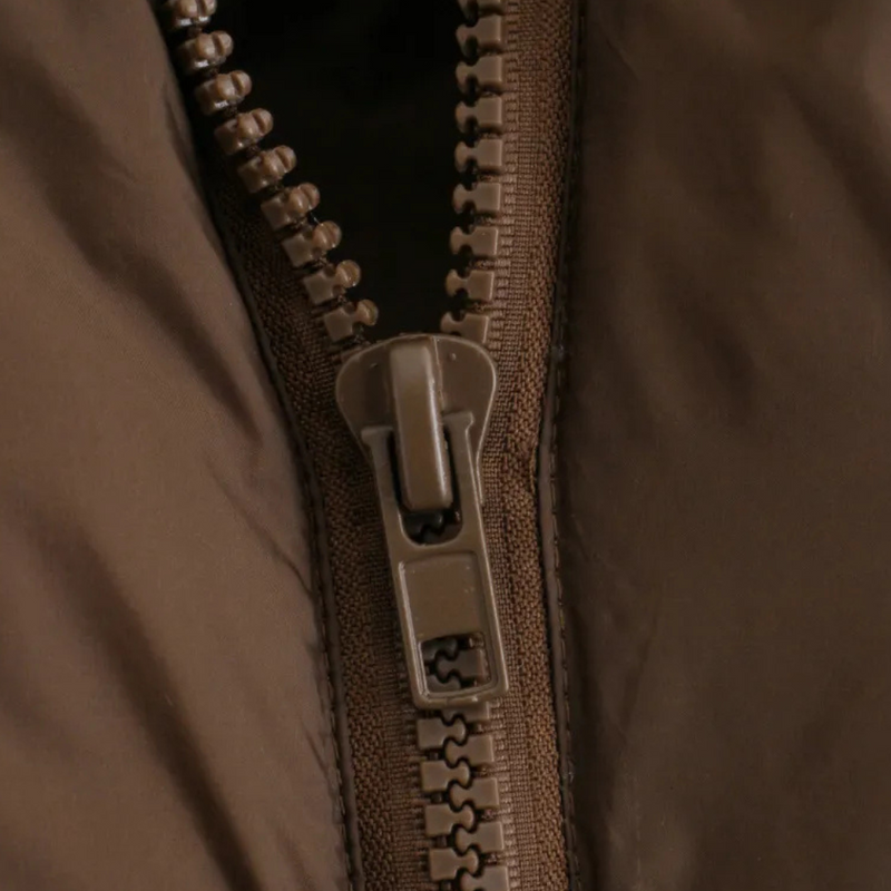 Brauner Reißverschluss aus Kunststoff auf Jacke, Nahaufnahme, Modeaccessoire, Detailansicht.