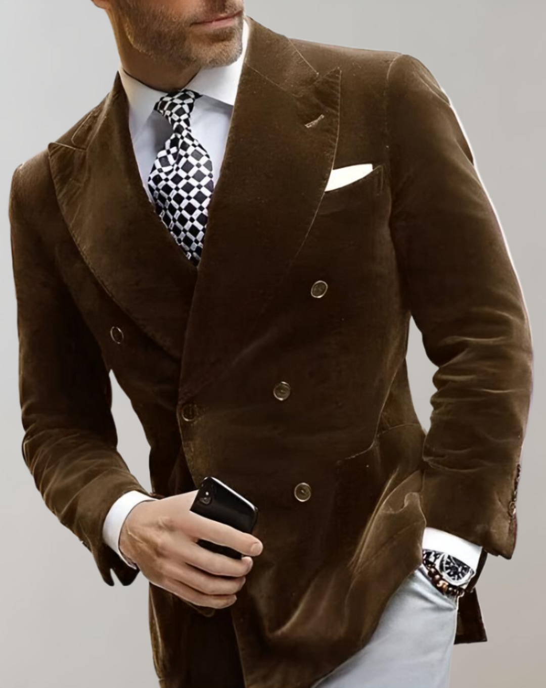 Mann im braunen Samtanzug mit Krawatte und Smartphone, eleganter Herrenmode-Look.