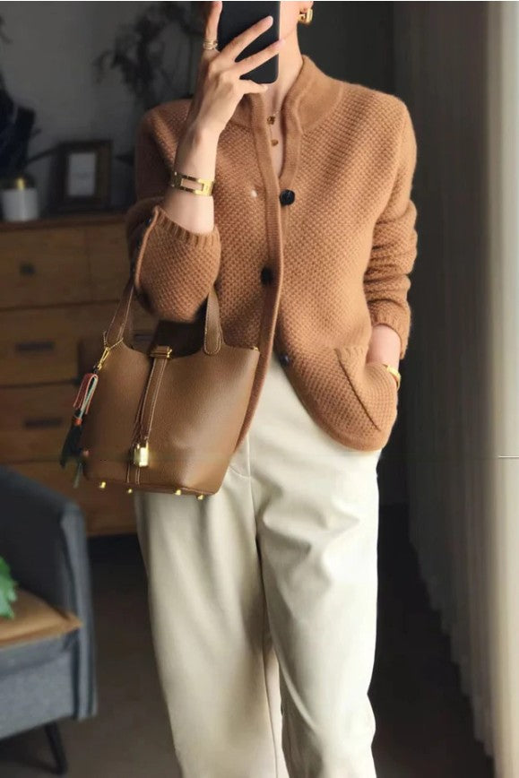 Frau in brauner Strickjacke und beiger Hose mit brauner Ledertasche, modisch, elegant.