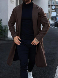 Mann in braunem Wollmantel, schwarzem Rollkragenpullover, dunkler Hose, weißen Sneakers.