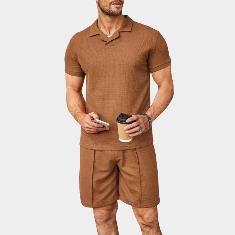 Mann in braunem Poloshirt und Shorts, hält Kaffeebecher und Smartphone, Sommermode Herren.