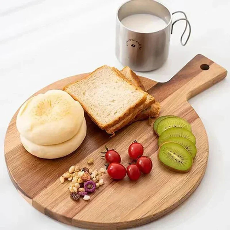 Holzbrett mit Toast, Brötchen, Kiwischeiben, Tomaten, Müsli und Tasse Milch auf weißem Hintergrund.