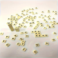 Viele Scrabble-Buchstaben aus Holz auf weißem Hintergrund verstreut.