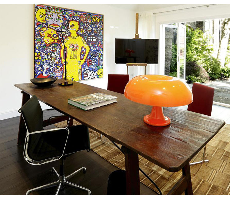 Moderner Konferenzraum mit Holztisch, orangefarbener Lampe, Kunstwerk und Flachbildschirm.