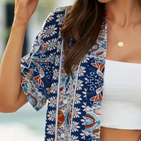 Frau in floralem Kimono, blau-weiß, mit goldener Halskette, modisch, sommerlich.