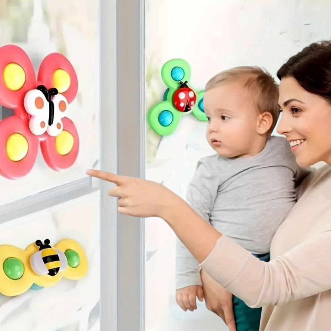 Kleinkind mit Mutter betrachtet bunte Saugnapf-Schmetterlingsspielzeuge am Fenster.