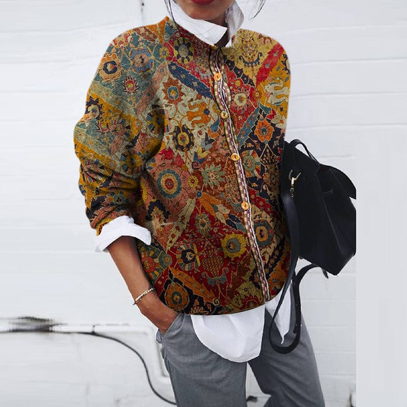 Frau trägt bunte Boho-Jacke mit ethnischem Muster, weißes Hemd, graue Hose, schwarze Tasche.