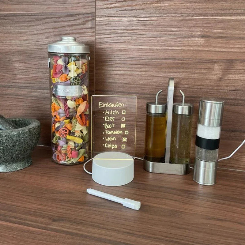 Bunte Nudeln im Glasbehälter, Mörser, Öl- und Essigspender, Salz- und Pfeffermühle auf Holzarbeitsplatte.