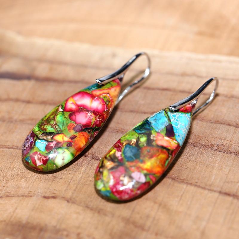 Bunte Harz-Ohrringe mit Blumenmuster auf Holzoberfläche, handgefertigter Schmuck.