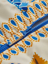 Nahaufnahme eines bunten Reißverschlusses auf gemustertem Stoff, blau-gelb, Textildesign.