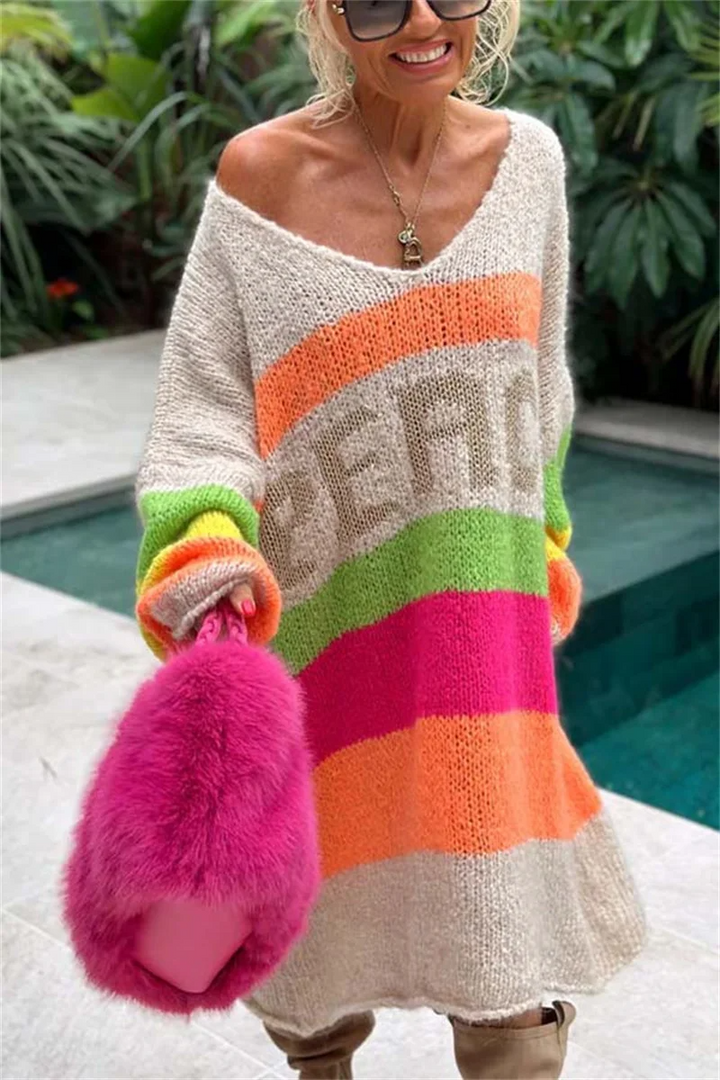 Frau in buntem Strickpullover mit Regenbogenstreifen und pinker Plüschhandtasche.