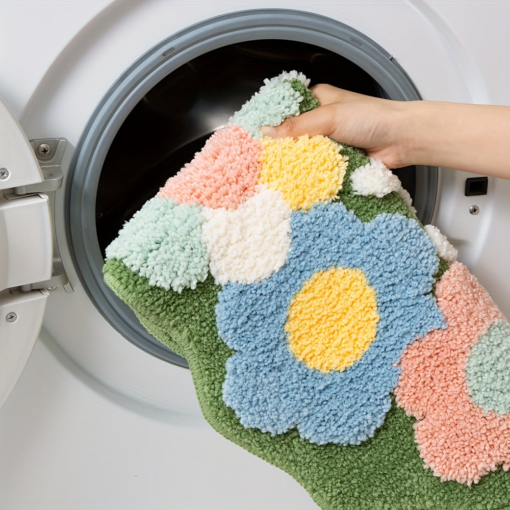 Bunte Blumen-Badmatte aus Baumwolle wird in Waschmaschine gelegt, Hand hält Teppich.