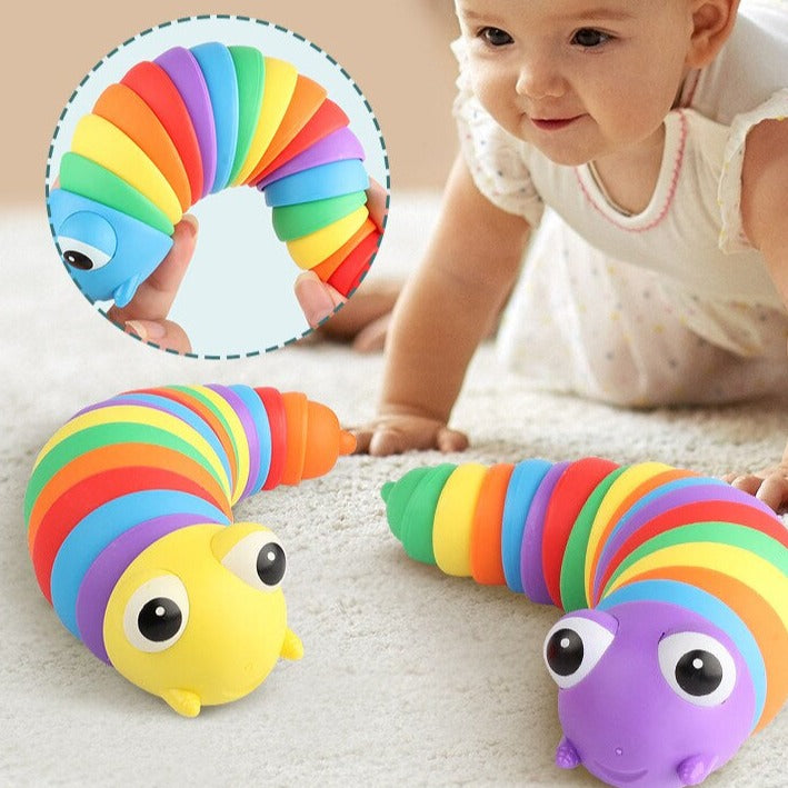 Baby spielt mit buntem, flexiblem Regenbogen-Raupen-Spielzeug aus Kunststoff auf Teppich.