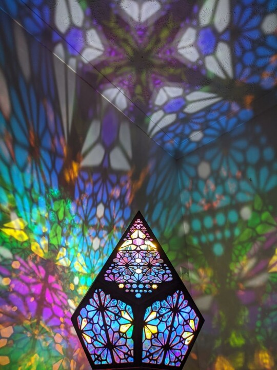 Buntes geometrisches Glasfenster mit Lichtreflexionen, dekorative Wandkunst, modern.