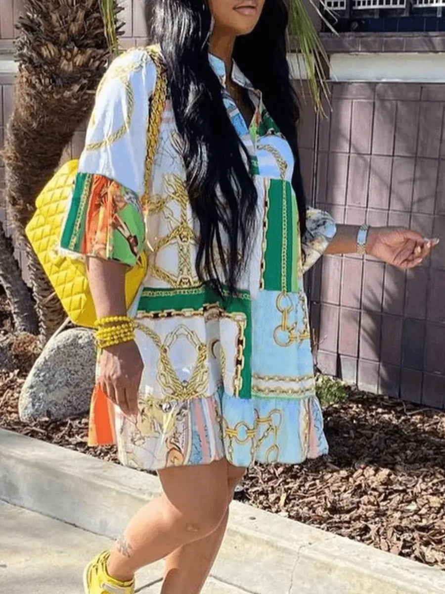 Frau in buntem Hemdkleid mit Kettenmuster, gelber Tasche und gelben Sneakers im Freien.