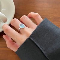 Silberring mit blauem Stein auf Hand, elegantes Schmuckdesign, Damenmode, Nahaufnahme.