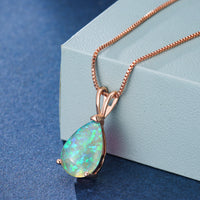 Opal-Anhänger mit Roségoldkette, tropfenförmig, schillernd, auf blauem Hintergrund.