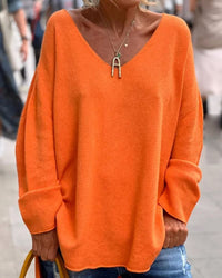 Frau in orangefarbenem Oversize-Pullover, V-Ausschnitt, lässiger Stil, Straßenmode.
