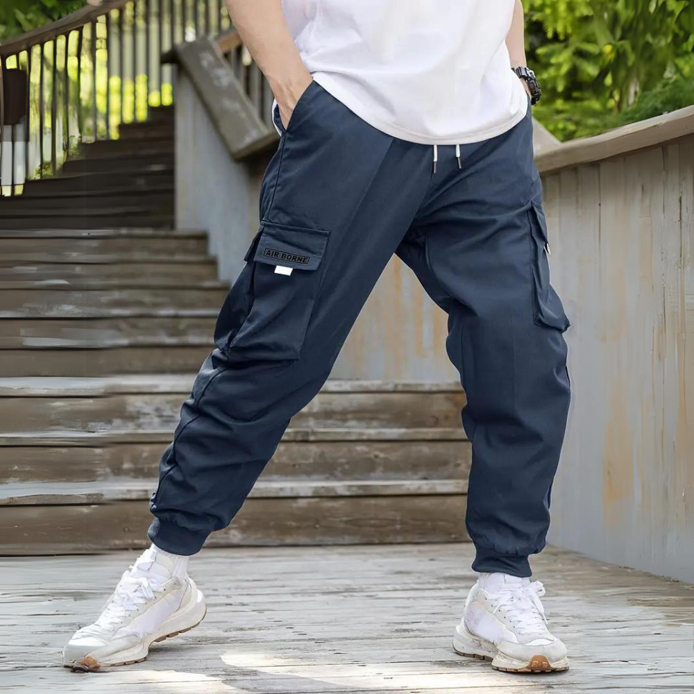 Mann in blauer Cargohose auf Treppe, lässiger Stil, Freizeitmode, Outdoor-Hose.