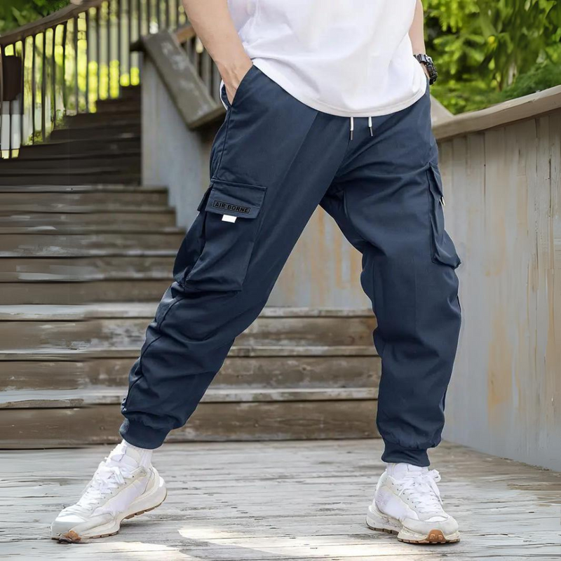 Mann in blauer Cargohose auf Treppe, lässiger Stil, Freizeitmode, Outdoor-Hose.