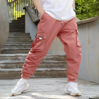 Mann in rosa Cargohose auf Treppe, lässiger Stil, weiße Sneaker, Outdoor-Mode.