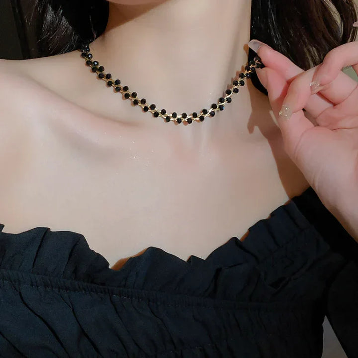 Frau trägt schwarzes Perlenhalsband, elegantes Schmuckstück, schwarzes Kleid, Abendmode.