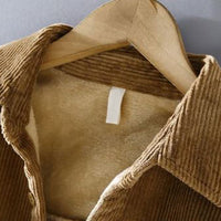 Braune Cordjacke mit Fellfutter auf Holzkleiderbügel, Wintermode, Herrenbekleidung.