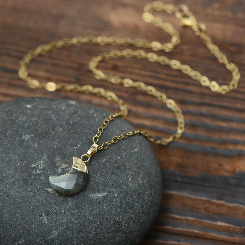 Goldene Mondstein-Anhänger-Halskette auf Holz, eleganter Schmuck, Damenaccessoire.